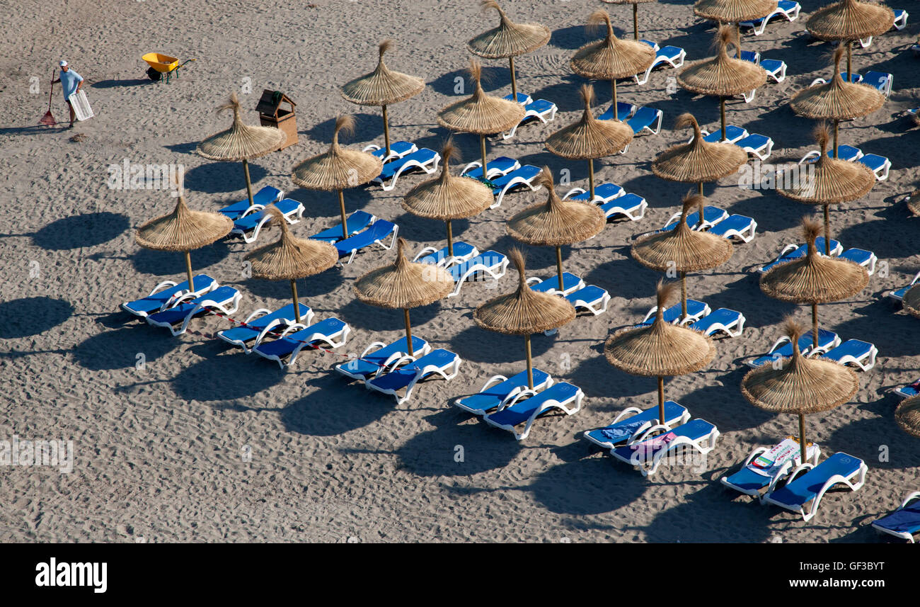 Un uomo che pulisce la spiaggia di mattina presto, prima di arrivare ai bagnanti, in Sant Elm, Mallorca, Spagna Foto Stock