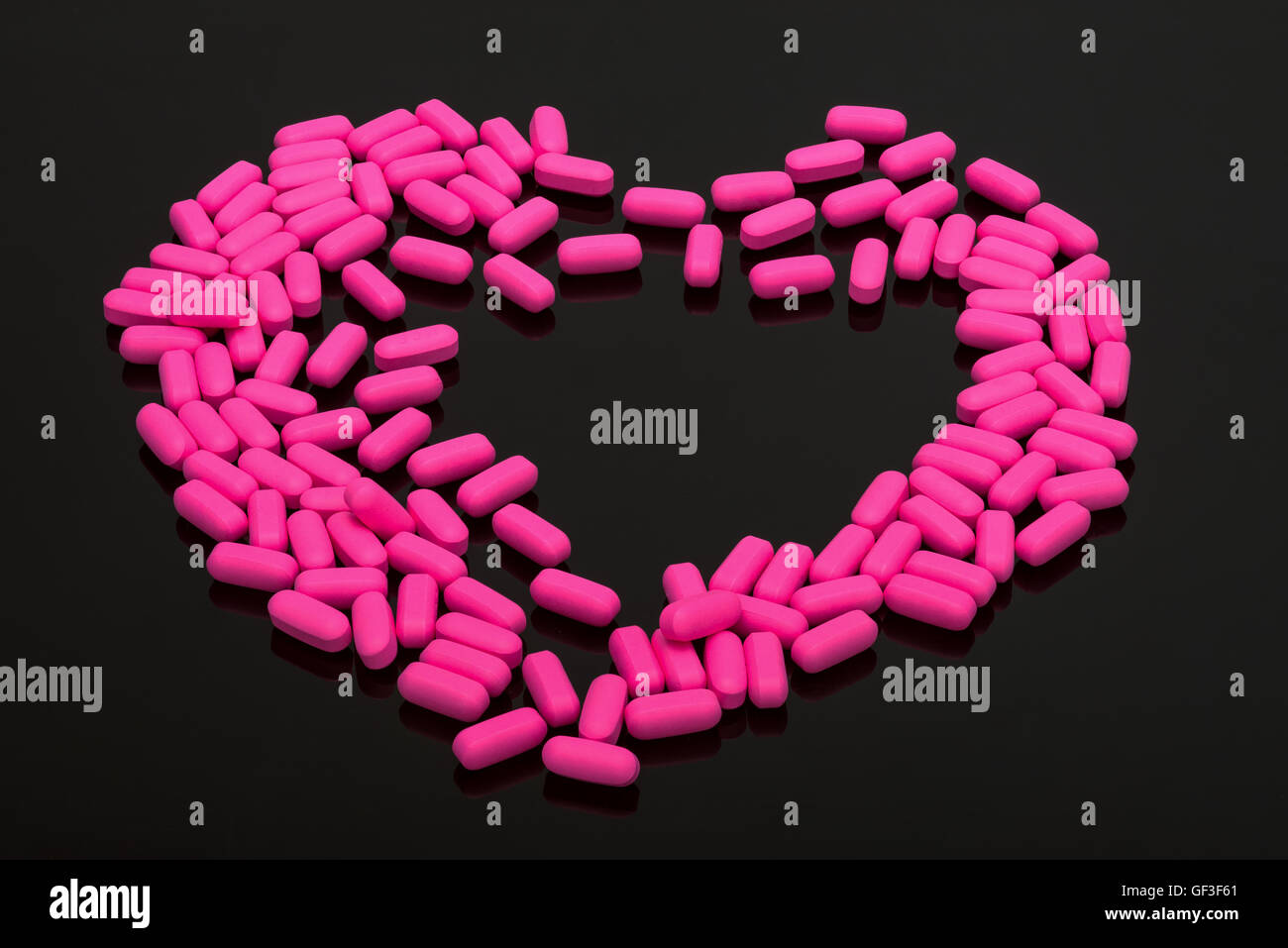 Emicrania pillole rosa capsule vitamine su sfondo nero Foto Stock