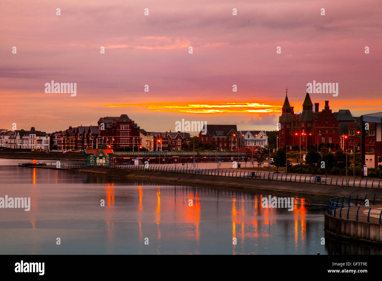 Southport, Merseyside, Regno Unito. 28 Luglio, 2016. Colorato sunrise cielo sopra la cittadina in stile vittoriano sul lungomare, con il Marine in barca il lago riflette l'ambra le luci di strada e quelle emergenti raggi del sole all'alba. La previsione è per pioggia di questa mattina, facilitando attraverso il pomeriggio, ma persistenti nel nord, più asciutta e più luminose più tardi con pesanti isolate, eventualmente thundery, docce. Credito: MediaWorldImages/Alamy Live News Foto Stock