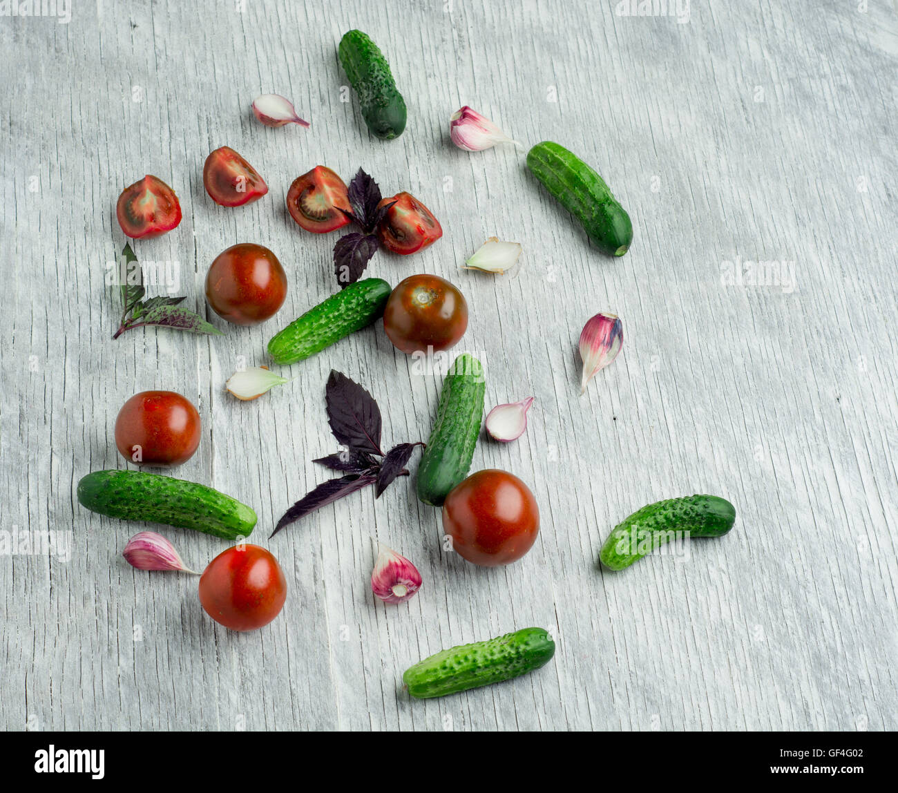Pomodori con basilico sul tavolo di legno dello sfondo. Composizione alimentare. Vista superiore Foto Stock