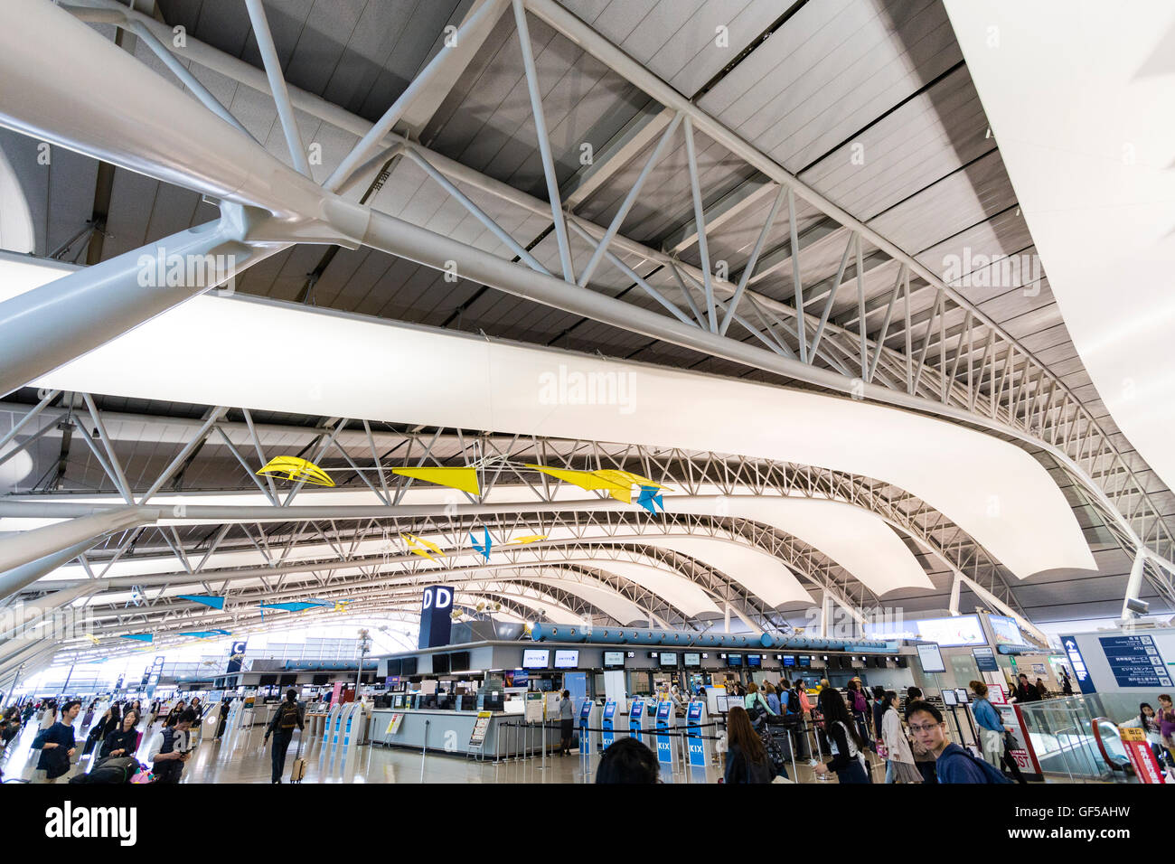 Giappone, Kansai, Aeroporto KIX. Interno del terminal uno edificio. International check-in. Vista generale della hall con file di banchi check-in e persone. Foto Stock