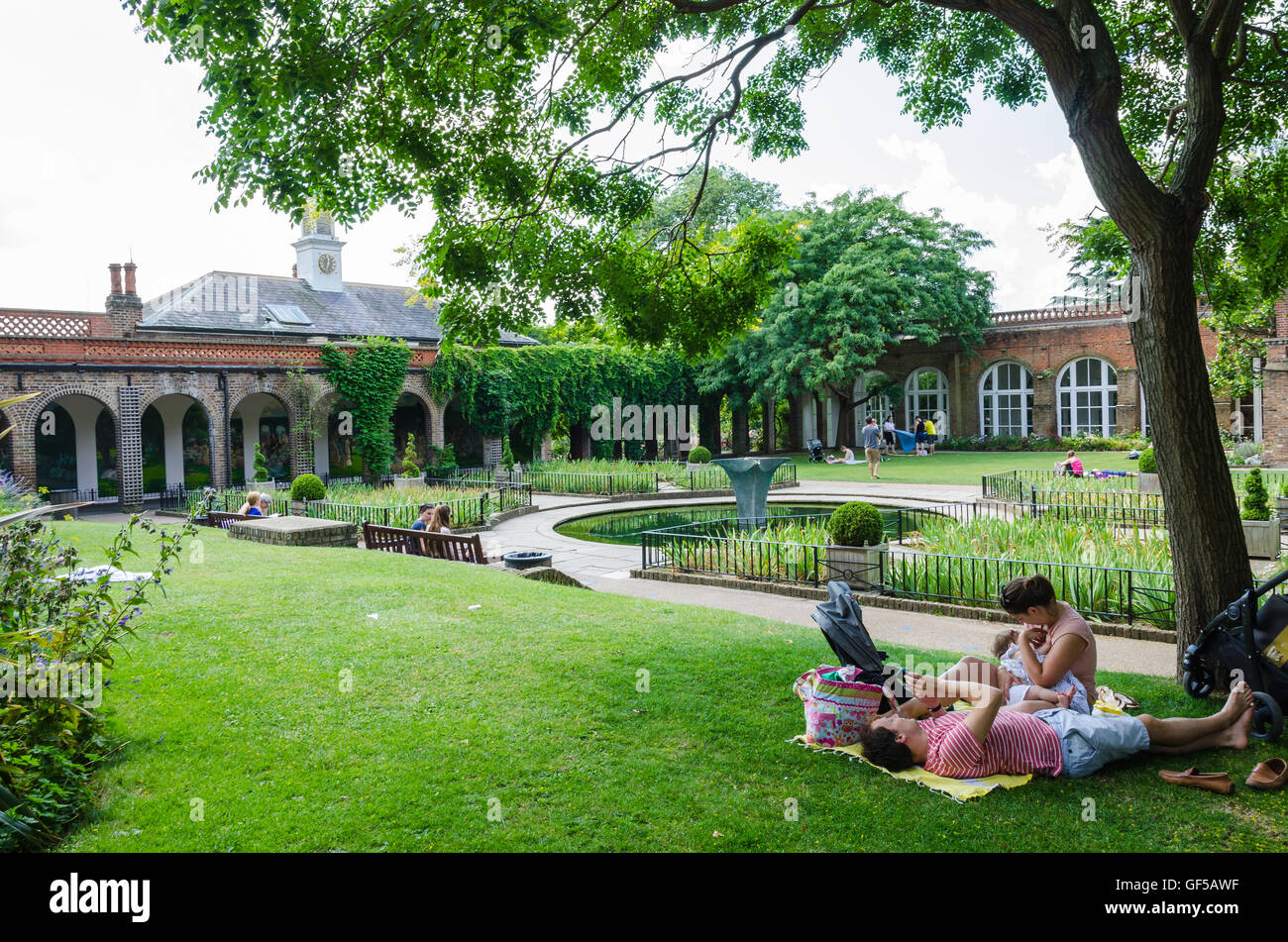 Una famiglia rilassarsi all'ombra di un albero nel giardino di Iris a Holland Park, Londra. Foto Stock