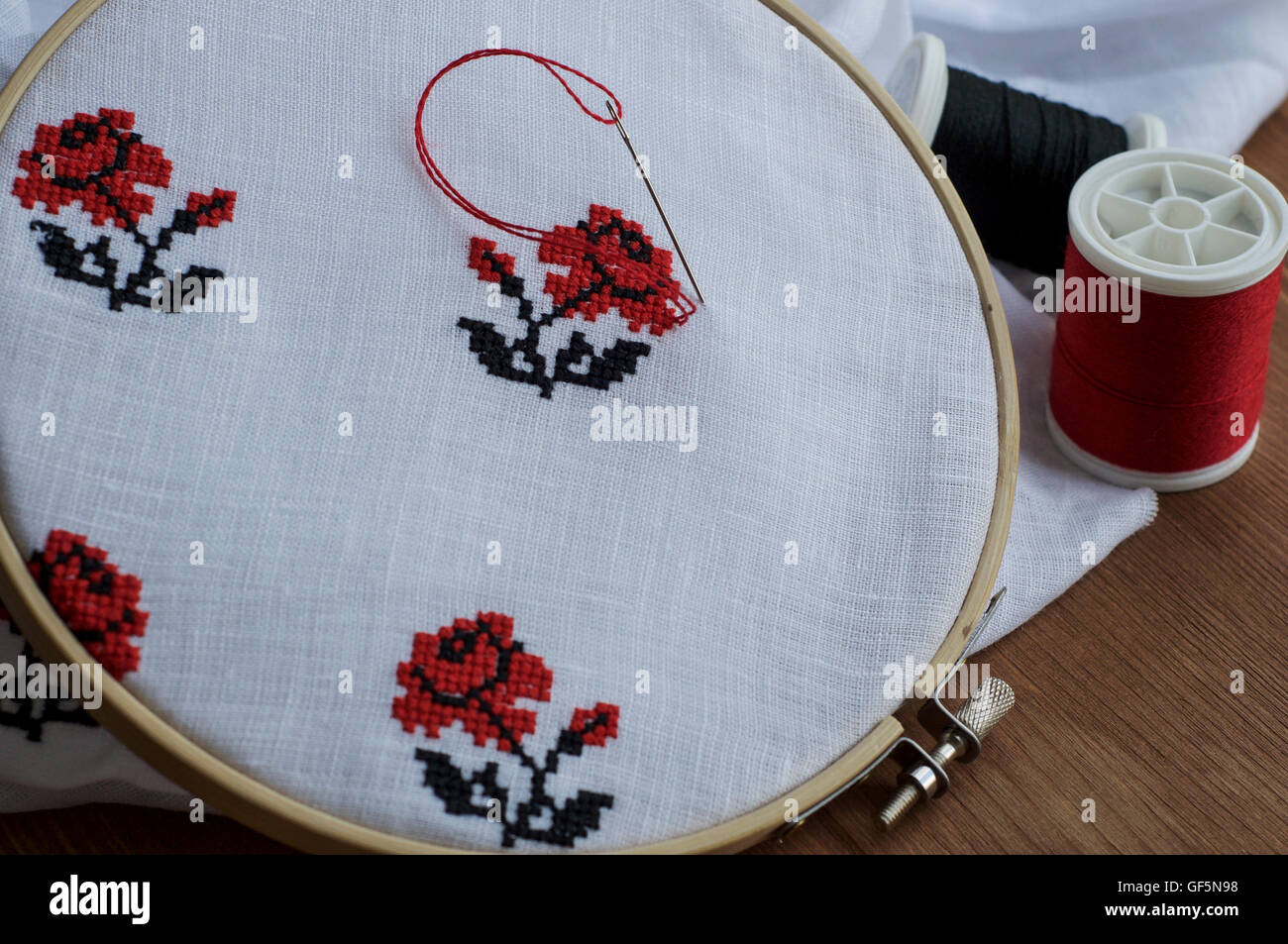Ricamo a mano a punto croce ornamento di fiori su un tessuto bianco nel  legno del telaio da ricamo rosso e il filo nero Foto stock - Alamy