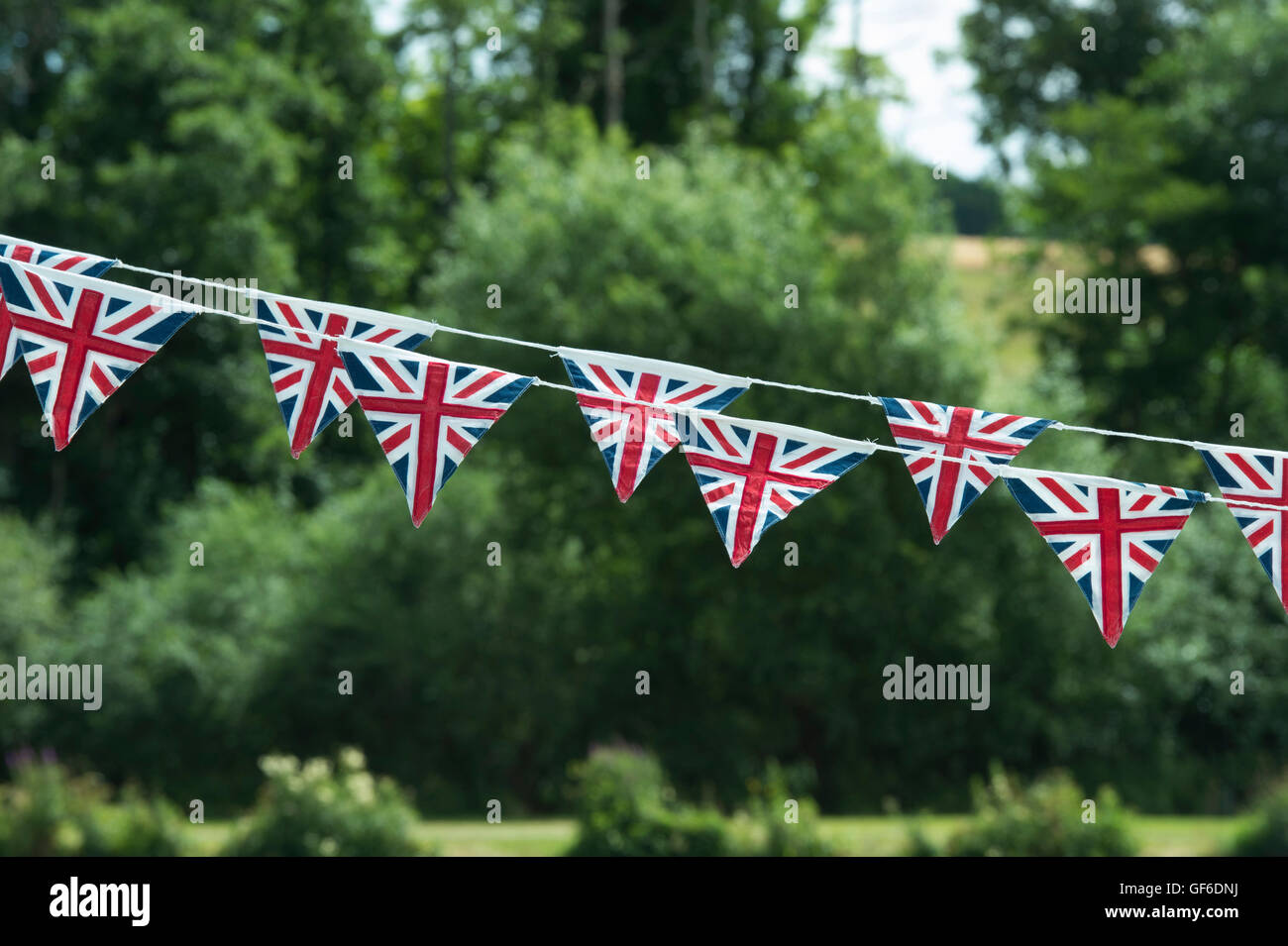 Union Jack flag bunting contro un sfondo ad albero Foto Stock