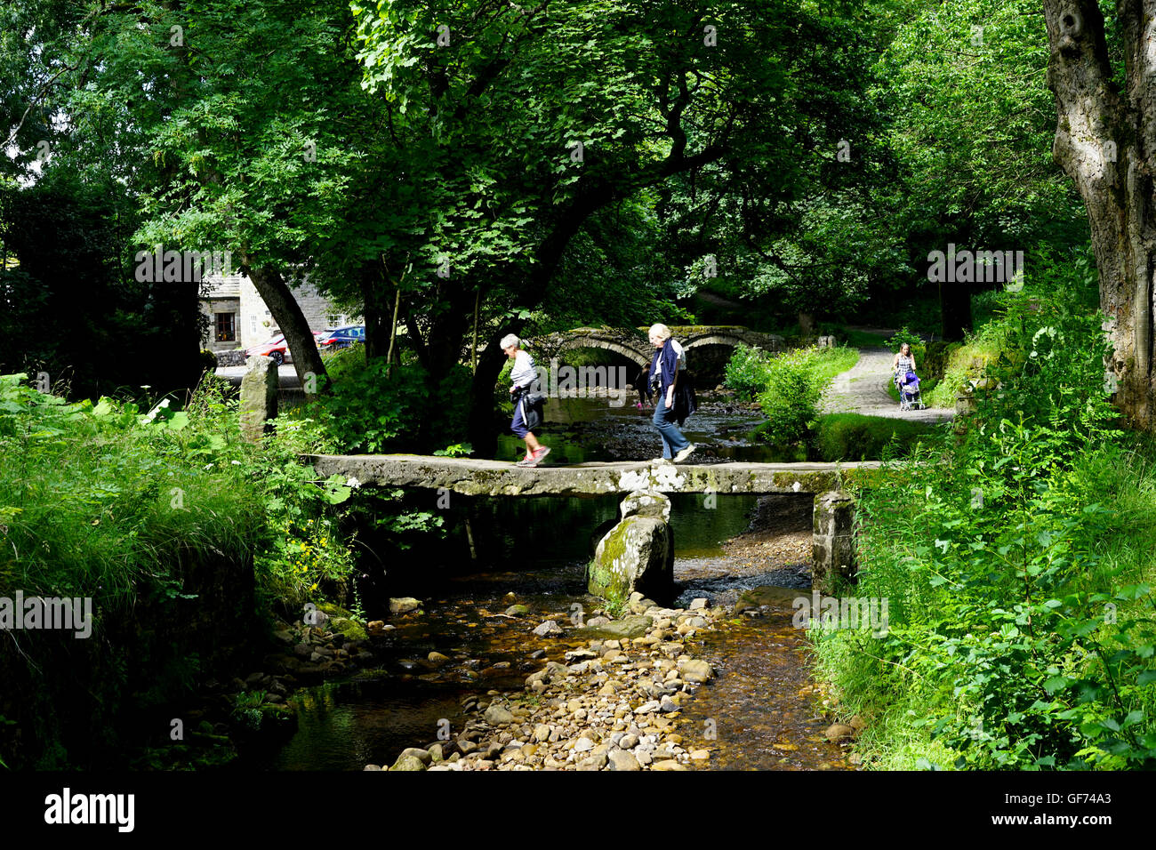 Due anziane signore attraversando Wycoller Beck sul battaglio Ponte a Wycoller,Trawden,,COLNE LANCASHIRE, Regno Unito. Foto Stock