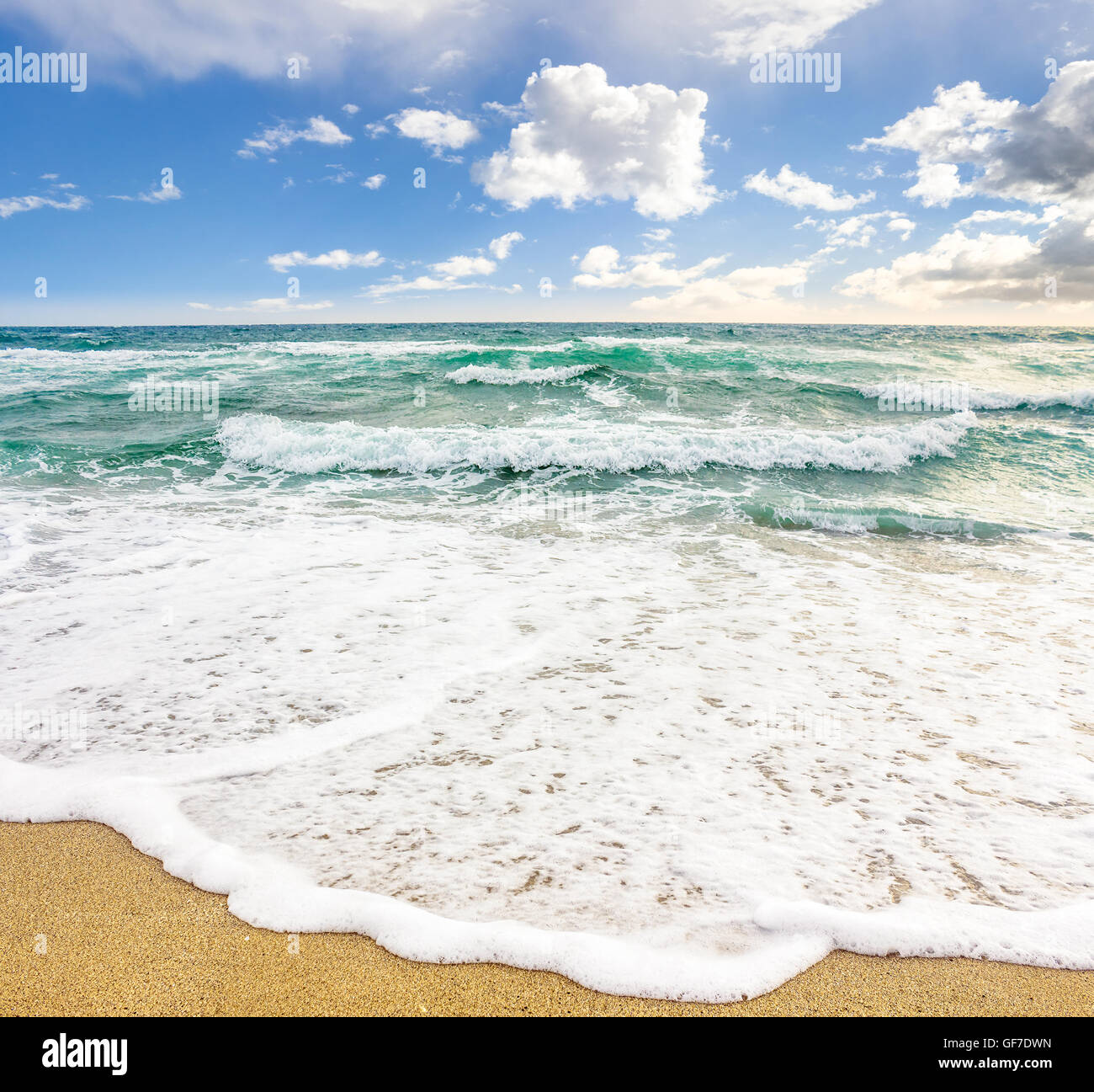 Sea Wave attacca la spiaggia di sabbia e di rottura su di essi Foto Stock