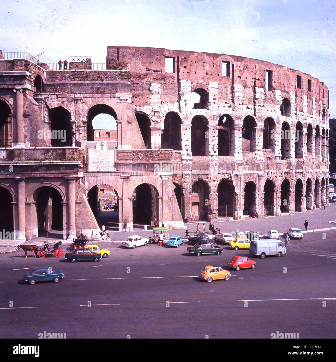 Anni sessanta, storico, Roma, Italia e automobili parcheggiate fuori il gigante Colosseo, il più grande e più famoso anfiteatro mai costruito. Foto Stock