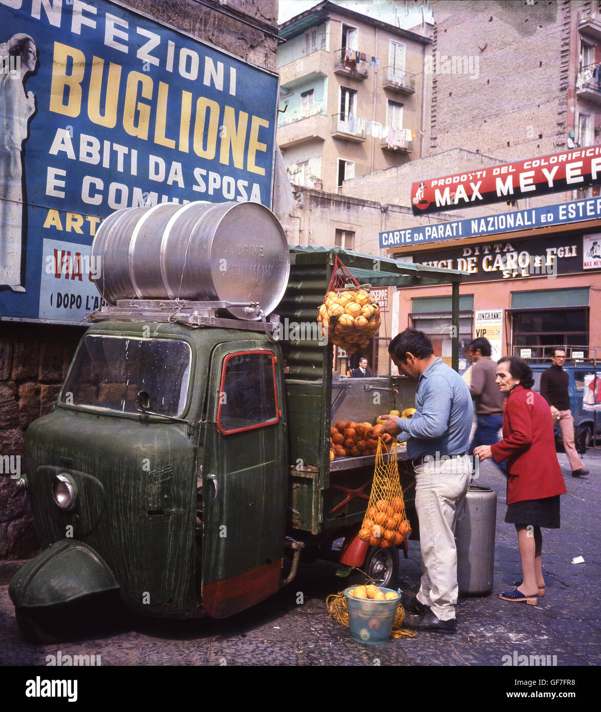 Anni sessanta, storica strada laterale a Roma, Italia, che mostra la popolazione locale e commerciante di fasci di vendita degli agrumi arance e limoni. Foto Stock