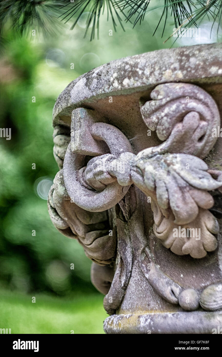 Close up di antica pietra ornata urna con profondità di campo per dare bel verde sfondo bokeh di fondo Foto Stock