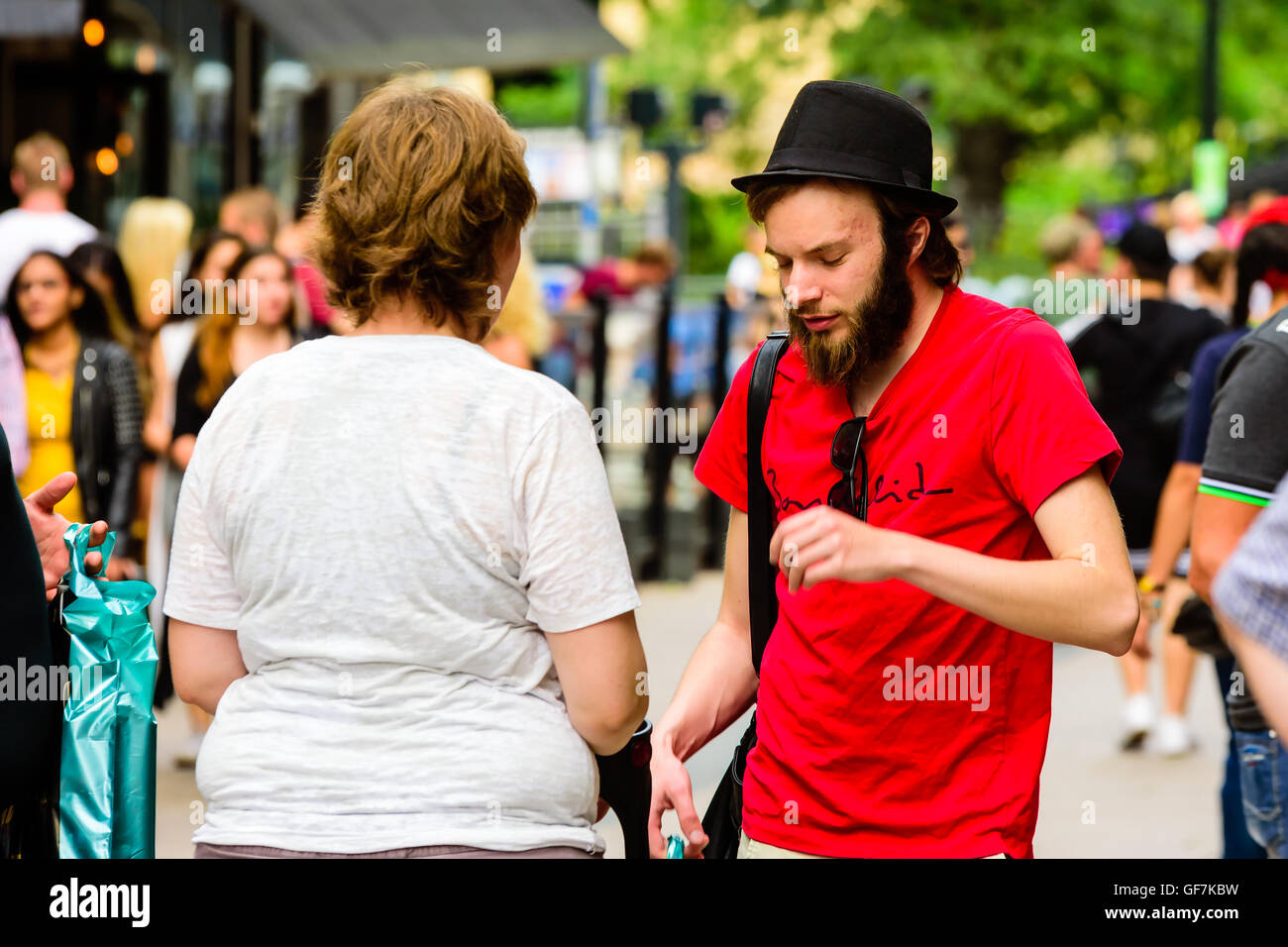 Goteborg, Svezia - 25 Luglio 2016: Sconosciuto giovane uomo adulto in barba e un cappello avente una discussione con una donna. Persone reali in ev Foto Stock