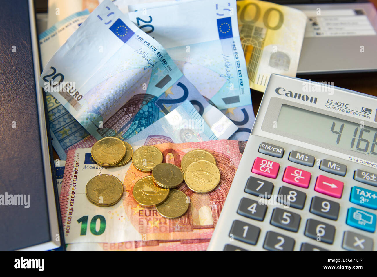 Varie le banconote e le monete in euro con una calcolatrice, il diario e il computer portatile. Foto Stock