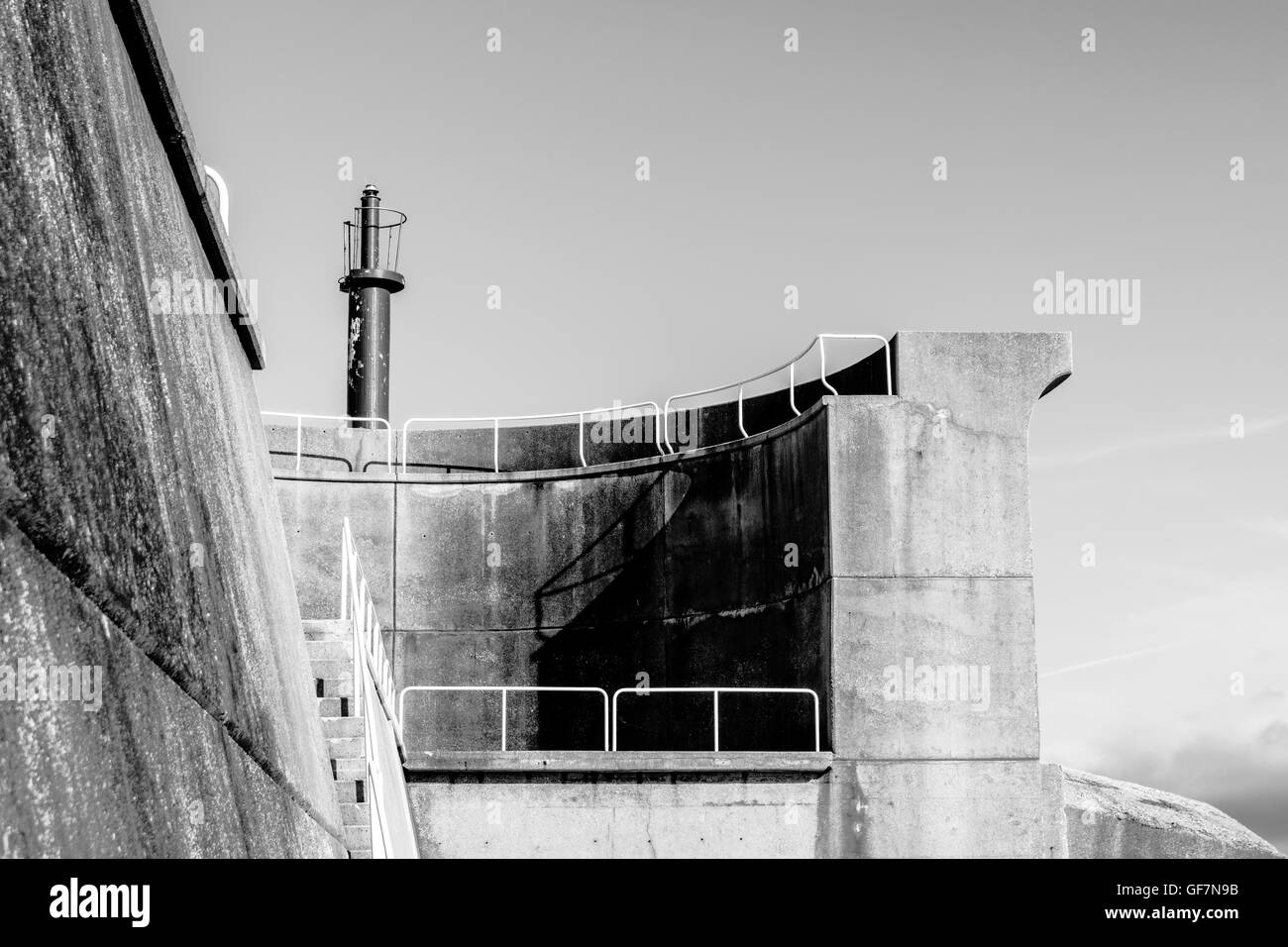 Vista parziale di dock di parete in calcestruzzo con il faro Foto Stock