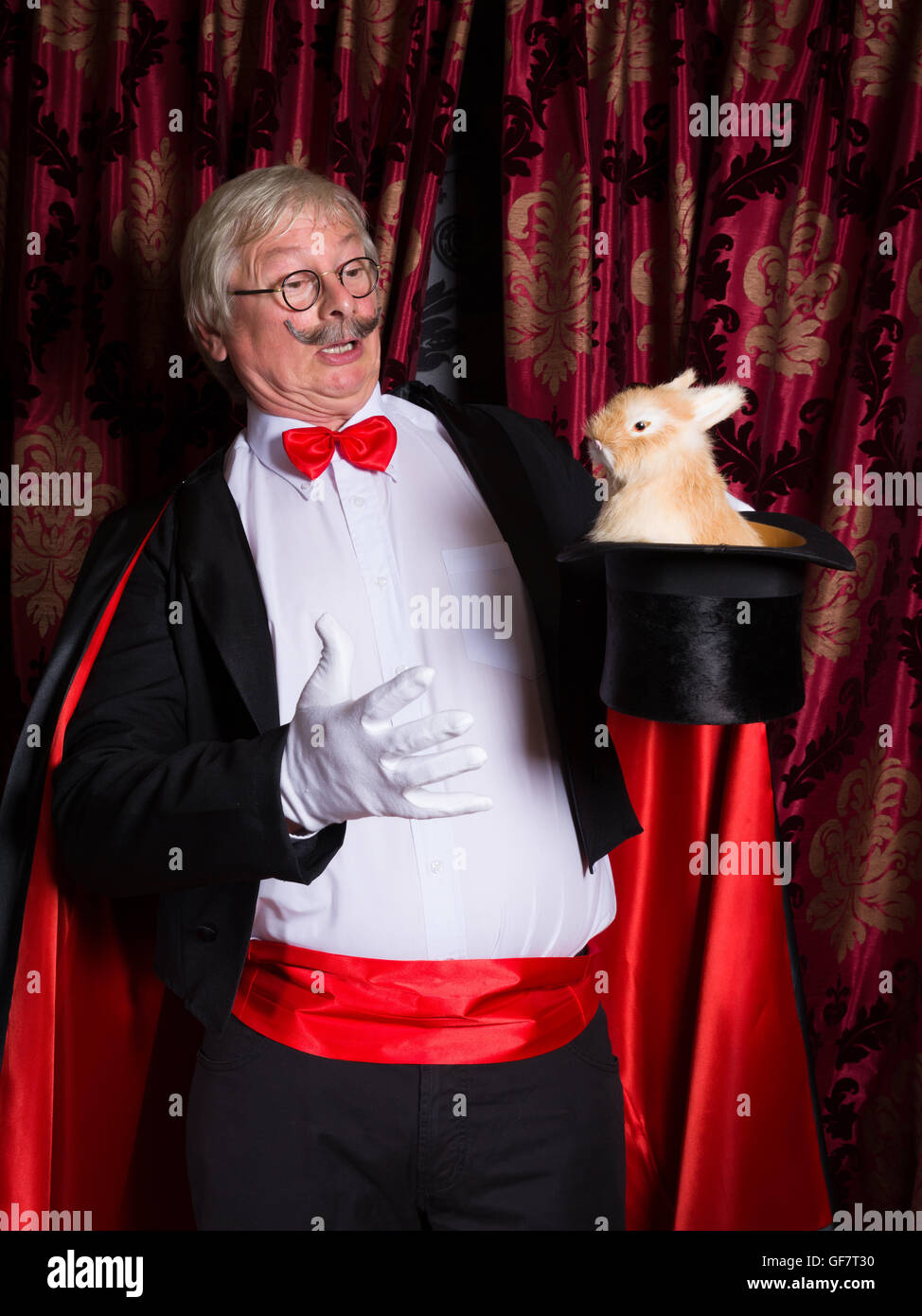 Funny illusionista sul palco con un coniglio nel suo top hat Foto Stock