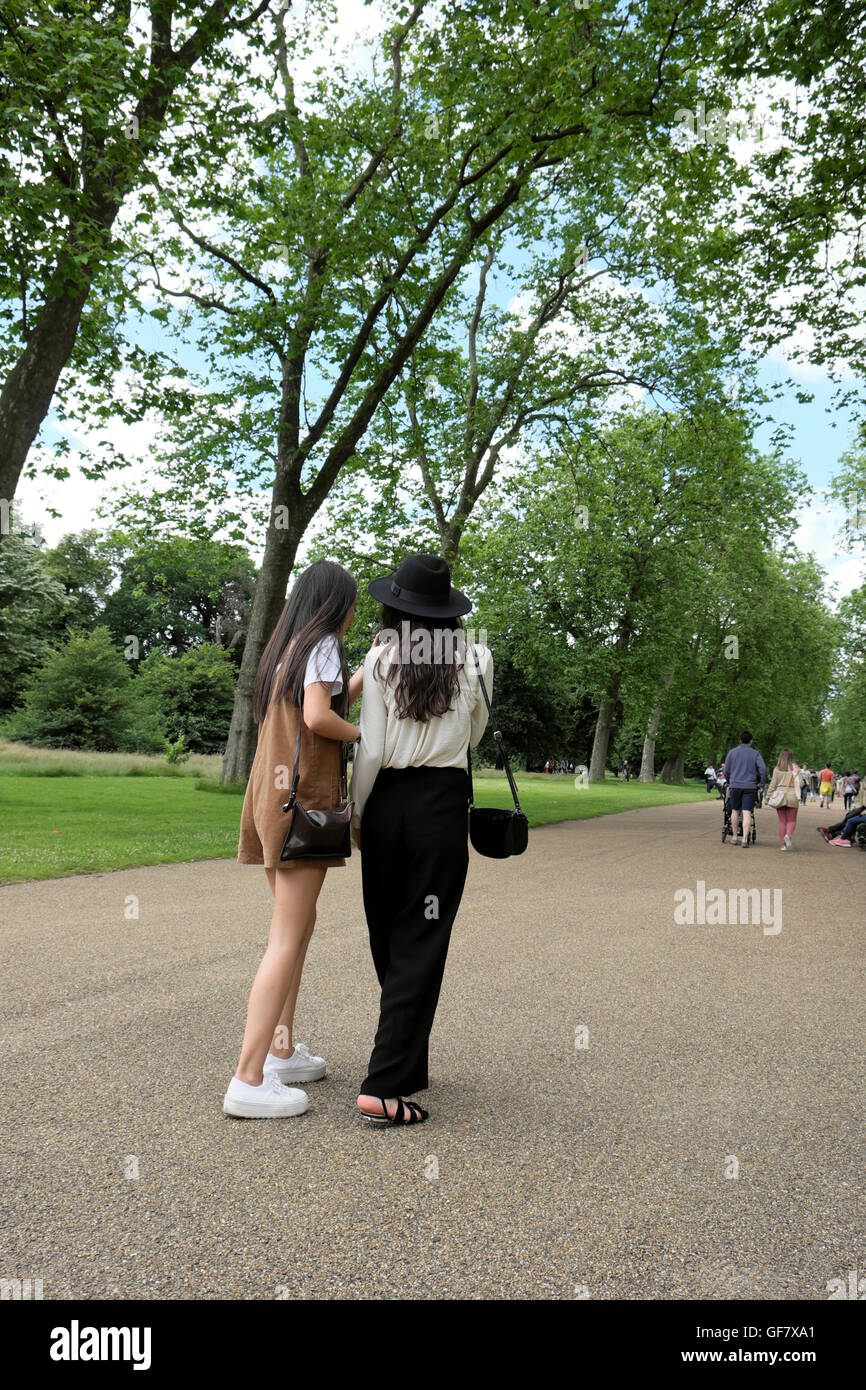 Vista posteriore di 2 Asia le giovani donne a piedi lungo un sentiero in estate 2016 Hyde Park, Londra UK KATHY DEWITT Foto Stock