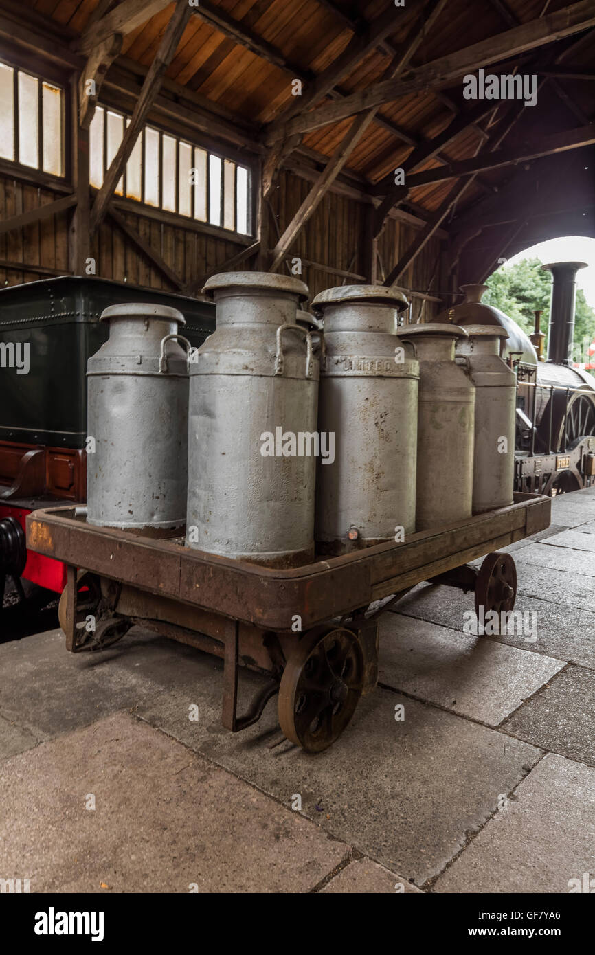 Bidoni per il latte su un carrello ferroviario in un capannone di treno al Didcot Railway Centre in Oxfordshire Foto Stock