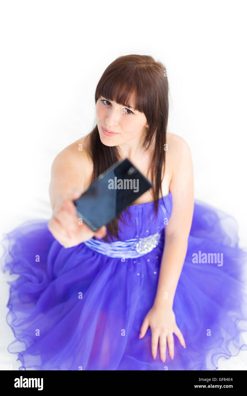 Una giovane ragazza in un blu abito da sera pone per la fotocamera cellulare autoritratto con emozioni Foto Stock