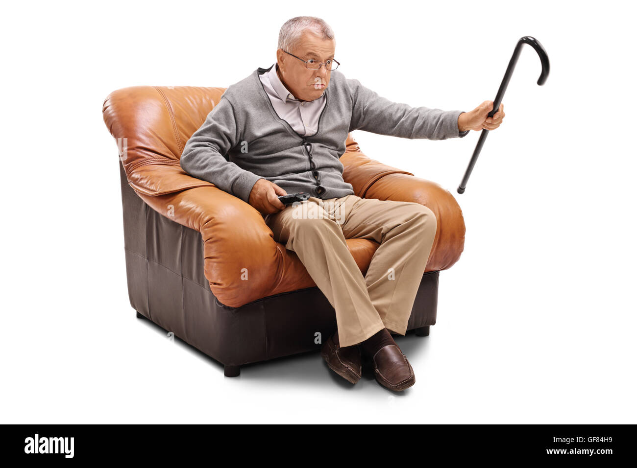 Infastiditi senior uomo guarda la TV seduti su una poltrona isolati su sfondo bianco Foto Stock