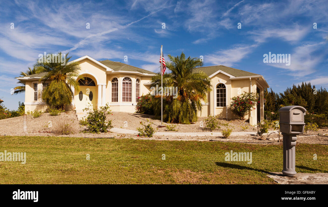 Tipico di Southwest Florida blocco di cemento e stucco a casa in campagna con palme e piante tropicali e fiori, erba Foto Stock