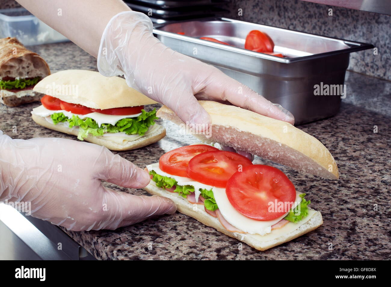 Lo Chef le mani preparano panini in una cucina commerciale Foto Stock