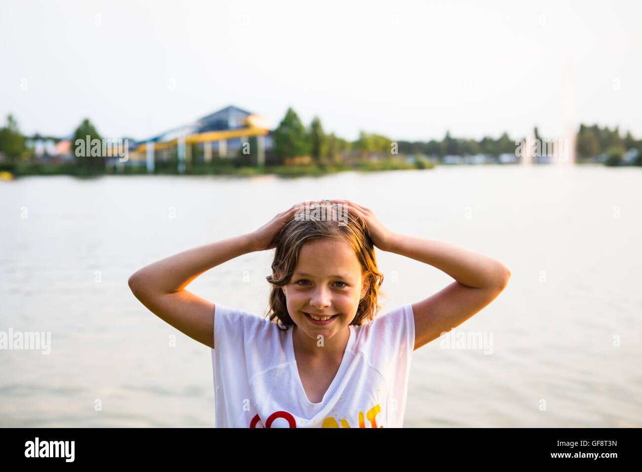 Ragazza sorridente in posa di fronte ad un lago turistico appena prima del tramonto a la sua vacanza Foto Stock