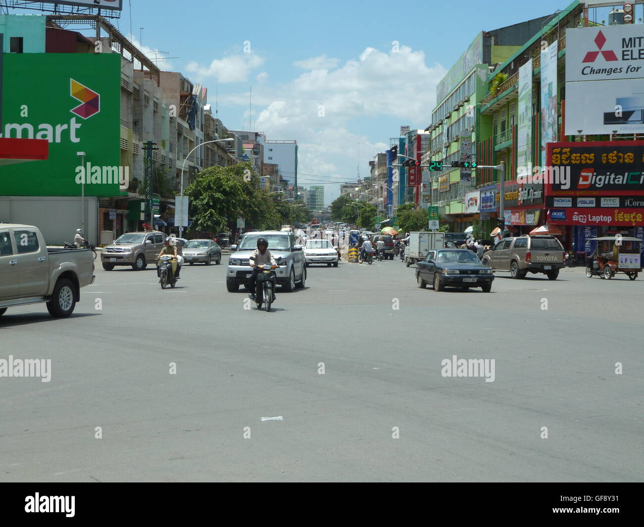 Foto di strada a Phnom Penh con persone che viaggiano in auto e in moto. Molto affollata e vivace città cambogiane. Foto Stock