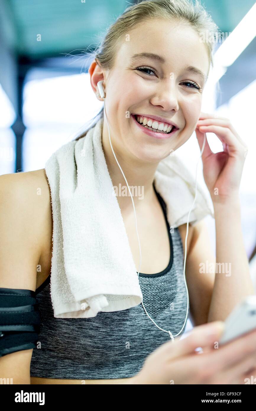 Proprietà rilasciato. Modello rilasciato. Giovane donna che indossa il braccio di regolazione della banda cuffie in palestra, ritratto. Foto Stock