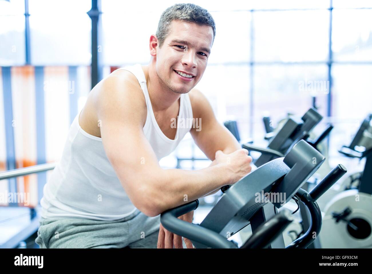 Proprietà rilasciato. Modello rilasciato. Ritratto di giovane uomo in appoggio mentre il lavoro in palestra, sorridente. Foto Stock