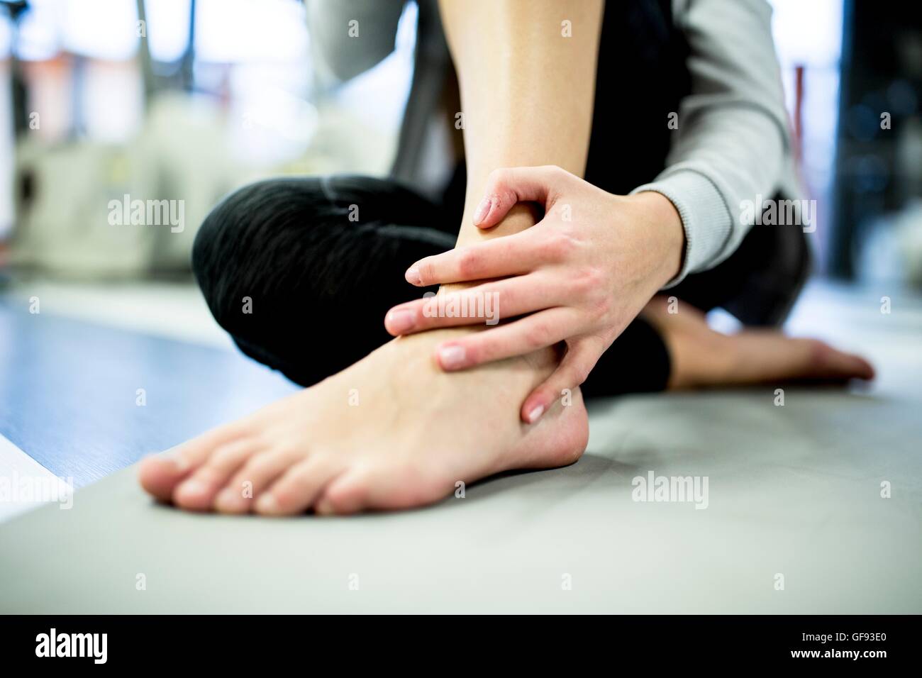 Proprietà rilasciato. Modello rilasciato. Giovane donna massaggiare la caviglia mentre avente il dolore della caviglia in palestra. Foto Stock