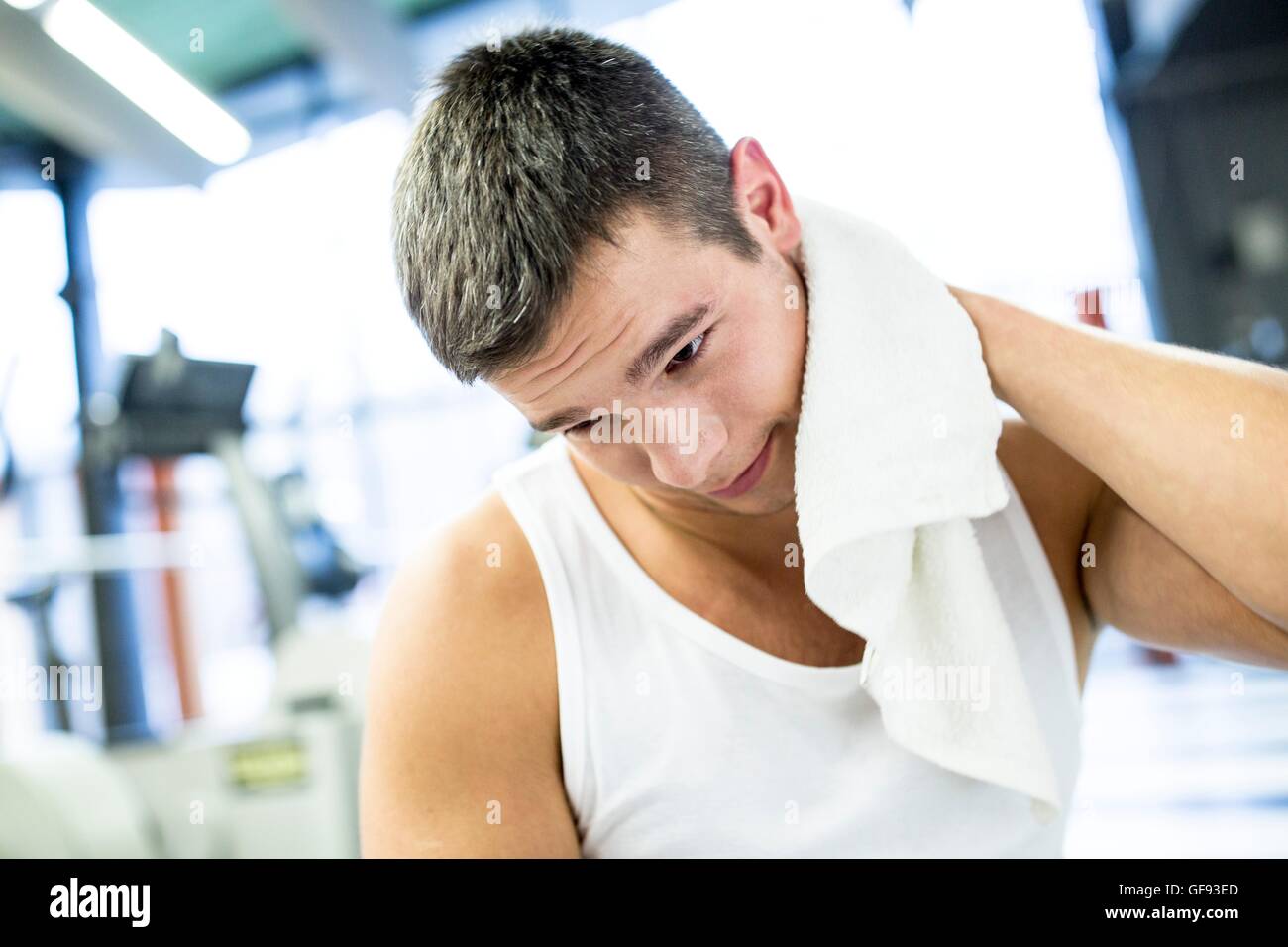 Proprietà rilasciato. Modello rilasciato. Giovane uomo tergi il suo sudore con asciugamano dopo esercizio in palestra. Foto Stock