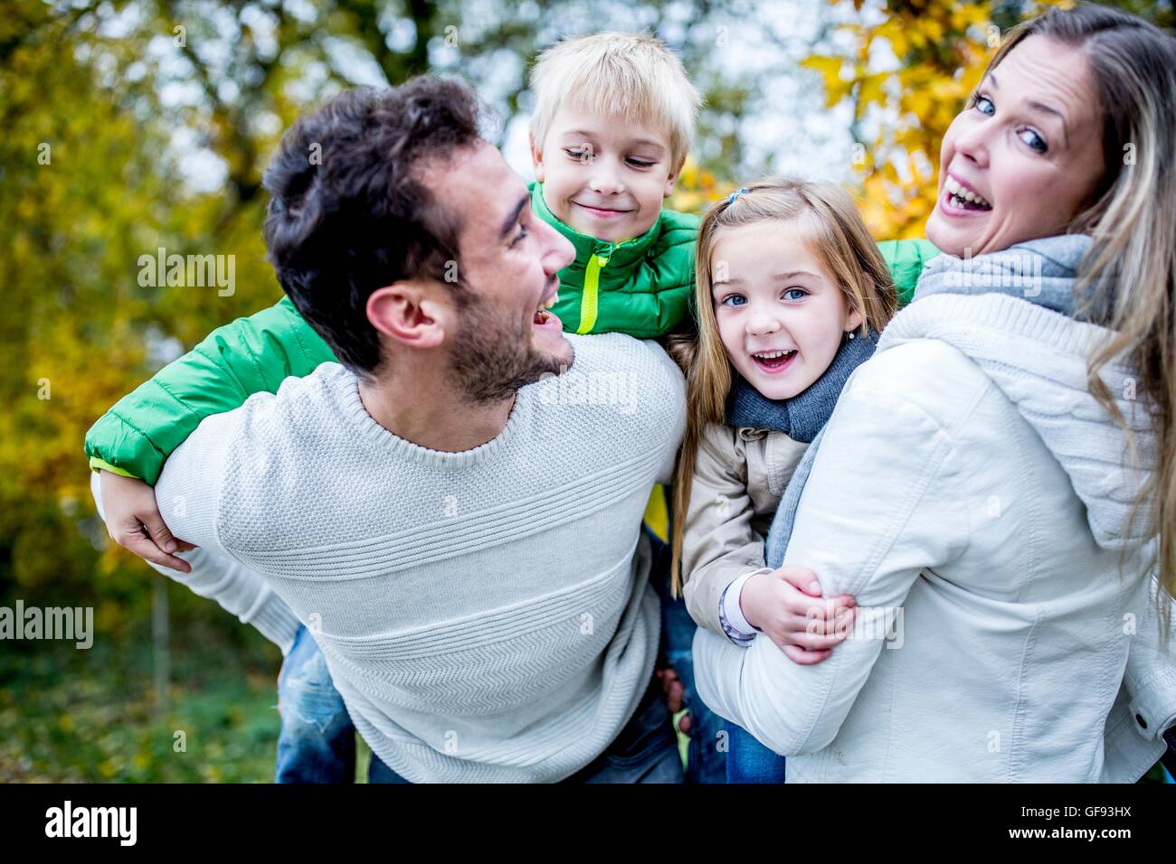 Modello rilasciato. I genitori che trasportano i loro figli in autunno, ridendo. Foto Stock