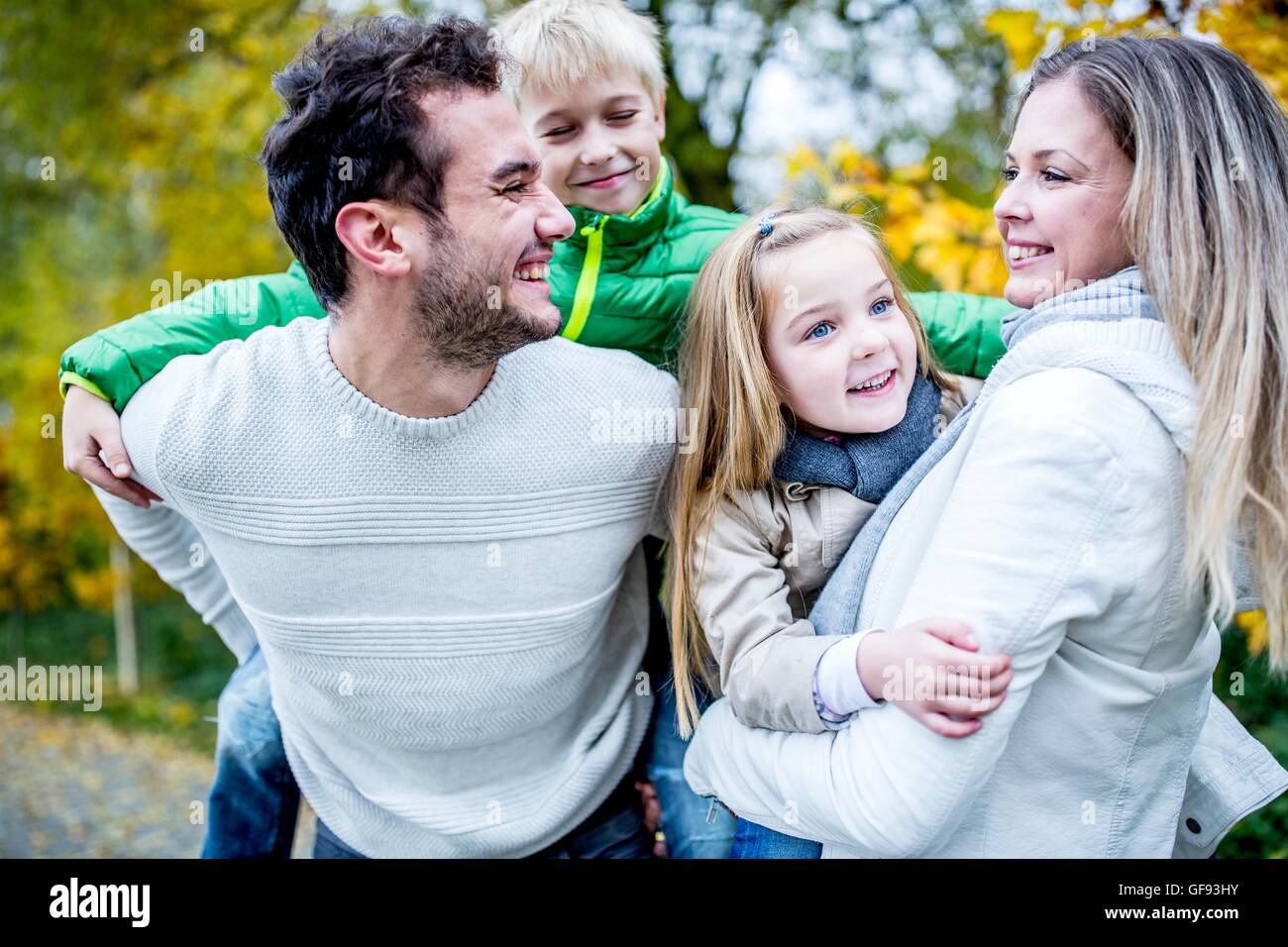 Modello rilasciato. I genitori che trasportano i loro figli in autunno, ridendo. Foto Stock