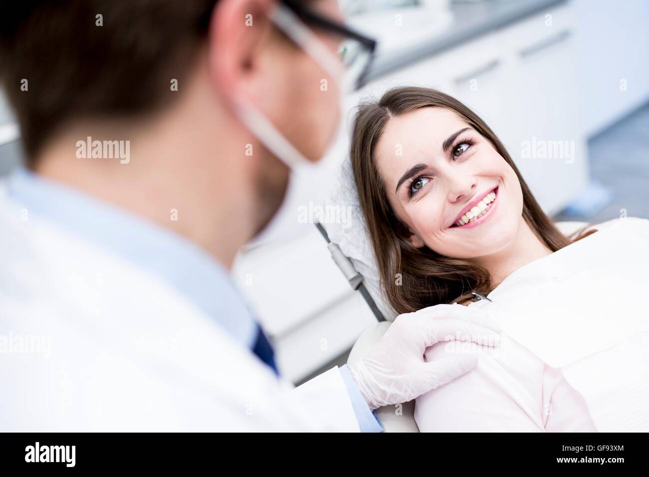 Modello rilasciato. Paziente guardando il dentista e sorridente in clinica del dentista. Foto Stock