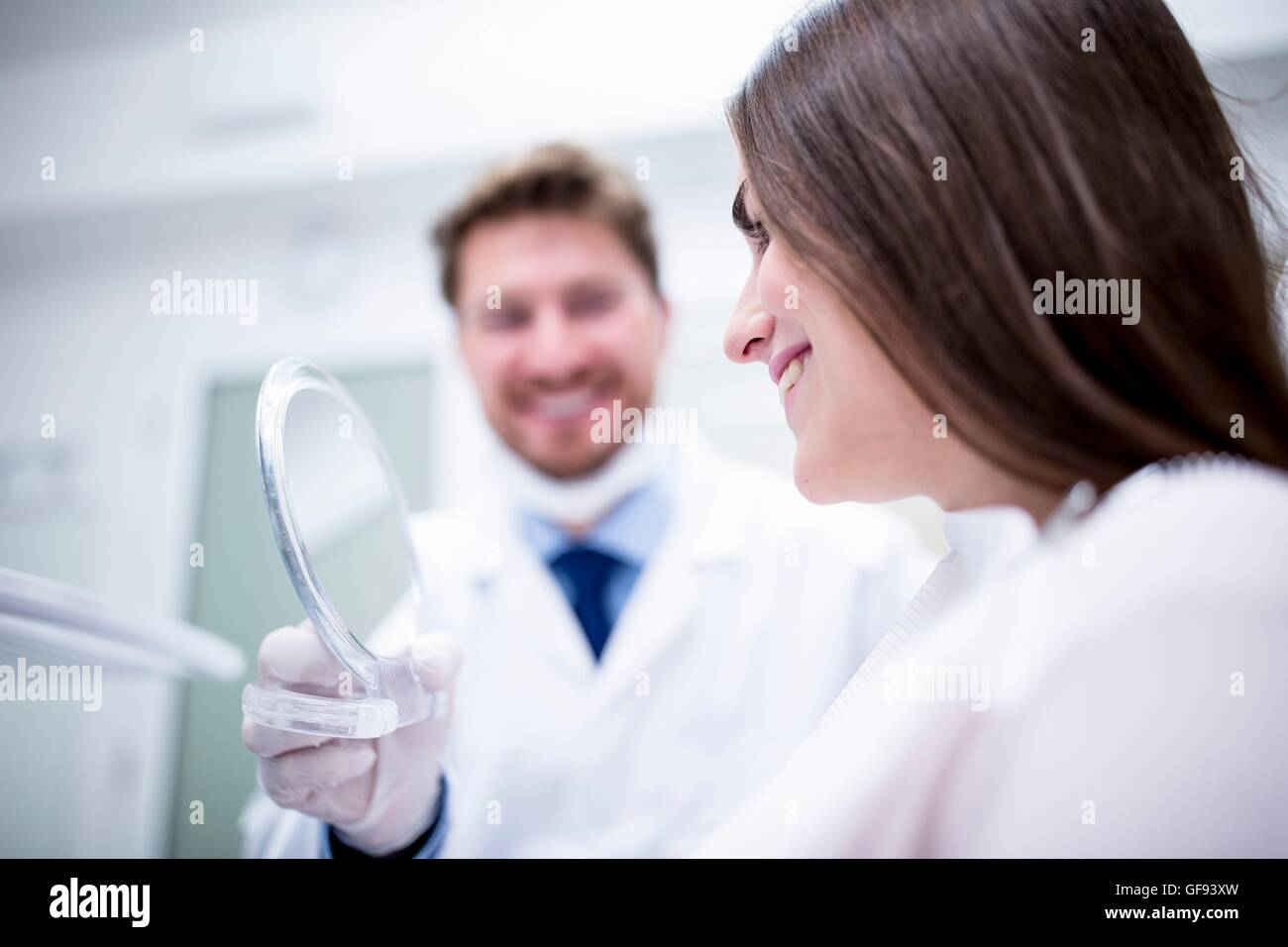 Modello rilasciato. Paziente in sedia dentisti controllare i suoi denti a specchio. Foto Stock