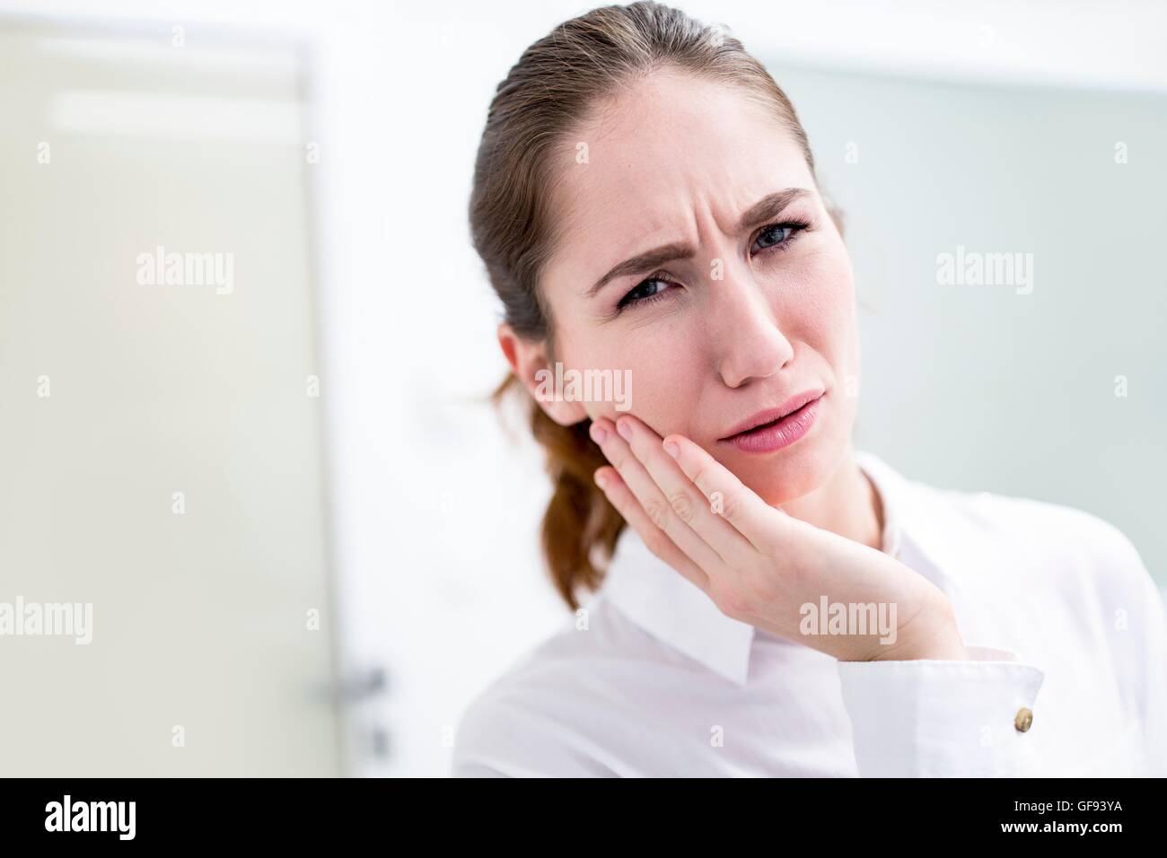 Modello rilasciato. Giovane donna che soffre di mal di denti, studio shot. Foto Stock