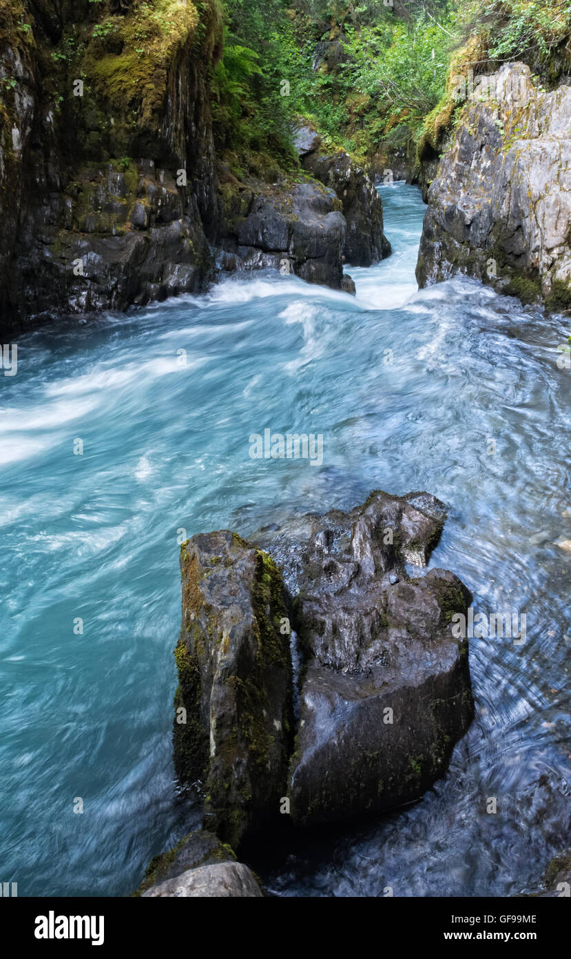 Un flusso riempita con polvere del ghiacciaio precipita attraverso una apertura in una parete di roccia. Foto Stock