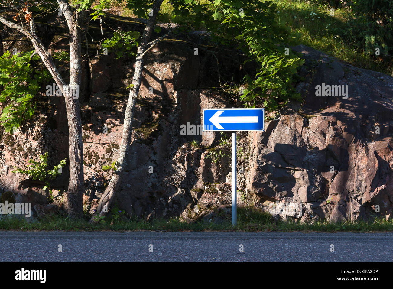 Cartello blu con la freccia sinistra sul lato della strada. Foto Stock