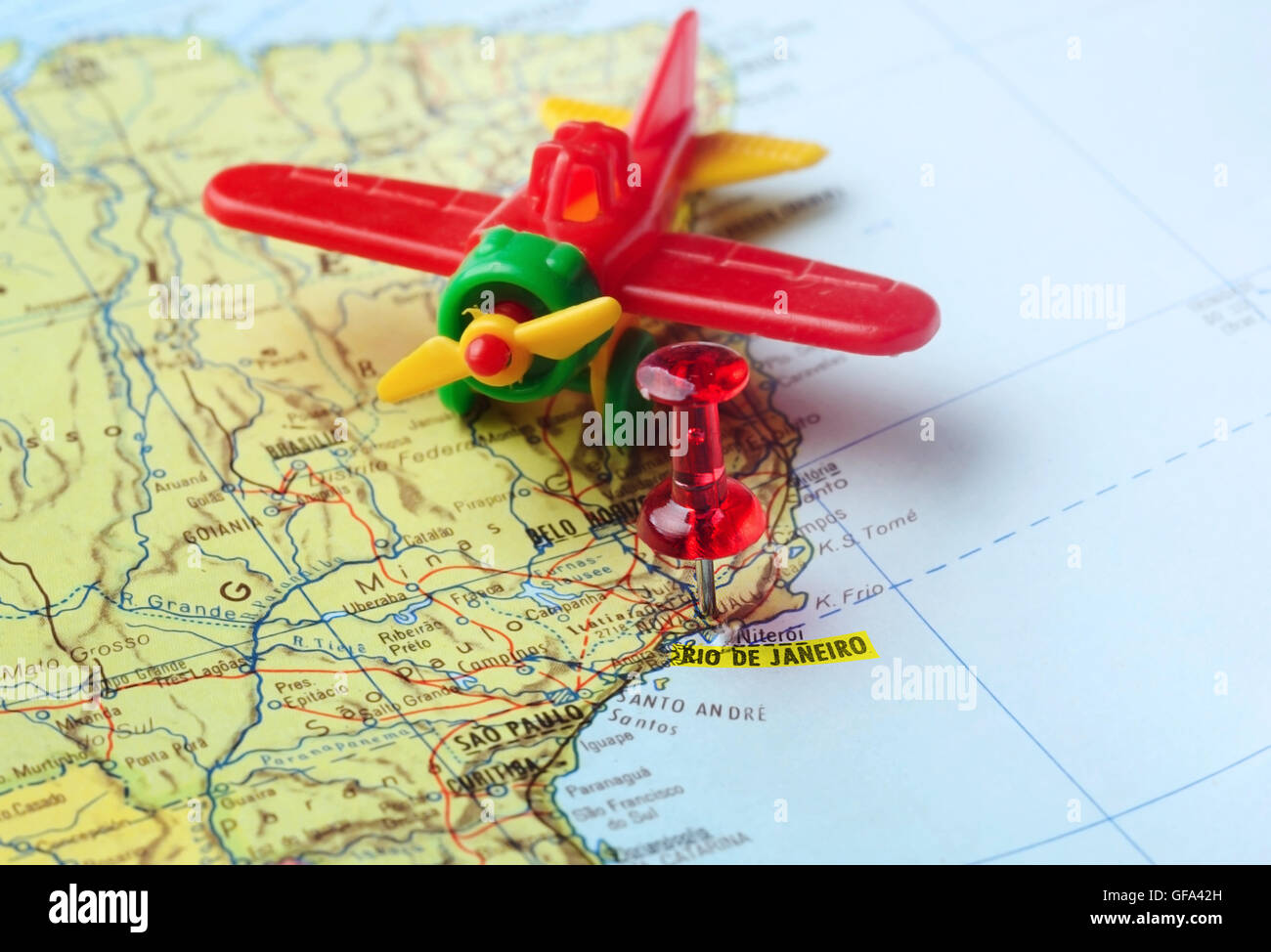 Close-up di una puntina rossa su una mappa di Rio de Janeiro e aereo - Concetto di viaggio Foto Stock