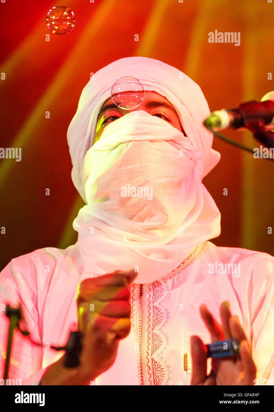 Un musicista con il gruppo Imarhan guarda una bolla soffiata dalla folla durante lo svolgimento del festival Womad, 28 luglio 2016. Foto Stock
