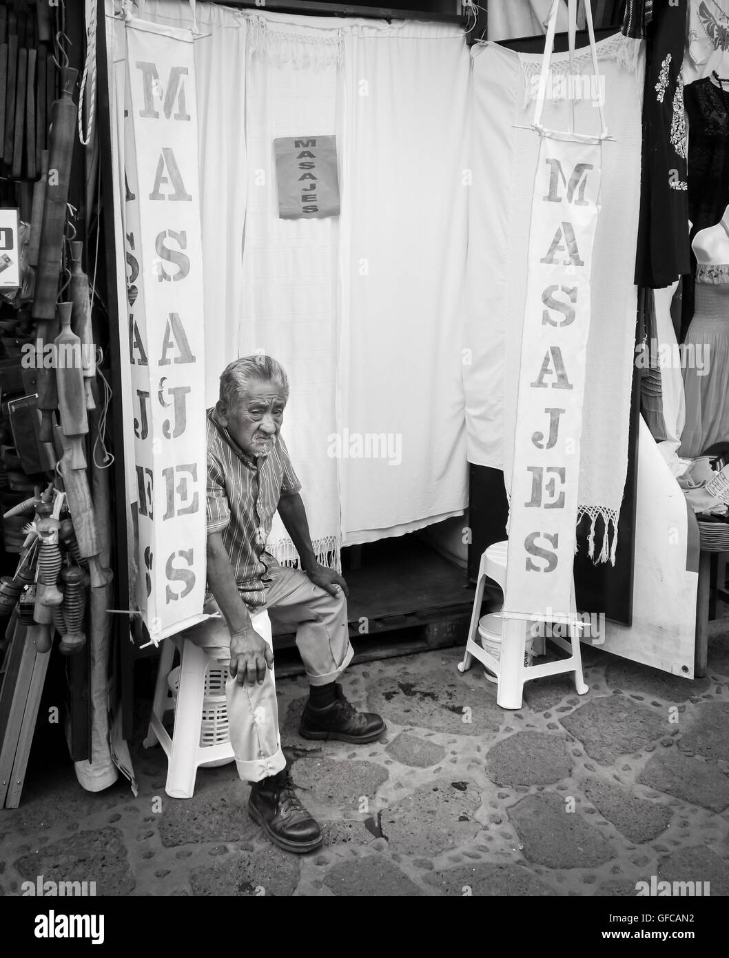 Massaggiatore vecchio seduto fuori il suo salone di massaggi Foto Stock