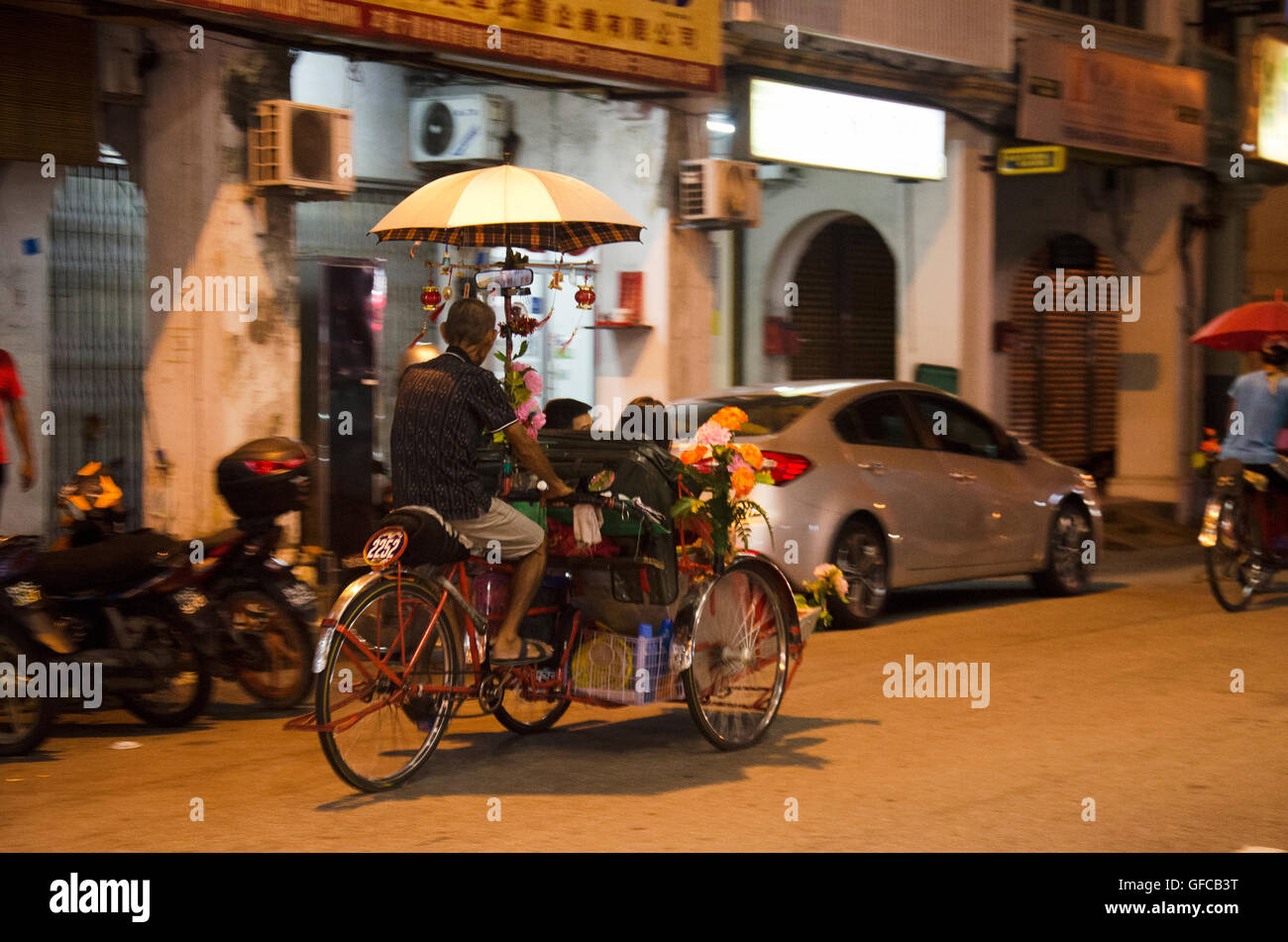 Malaysian persone a cavallo servizio rickshaw viaggiatore tour intorno a Georgetown città e arte di strada area al mercato notturno di alimenti in amore Foto Stock