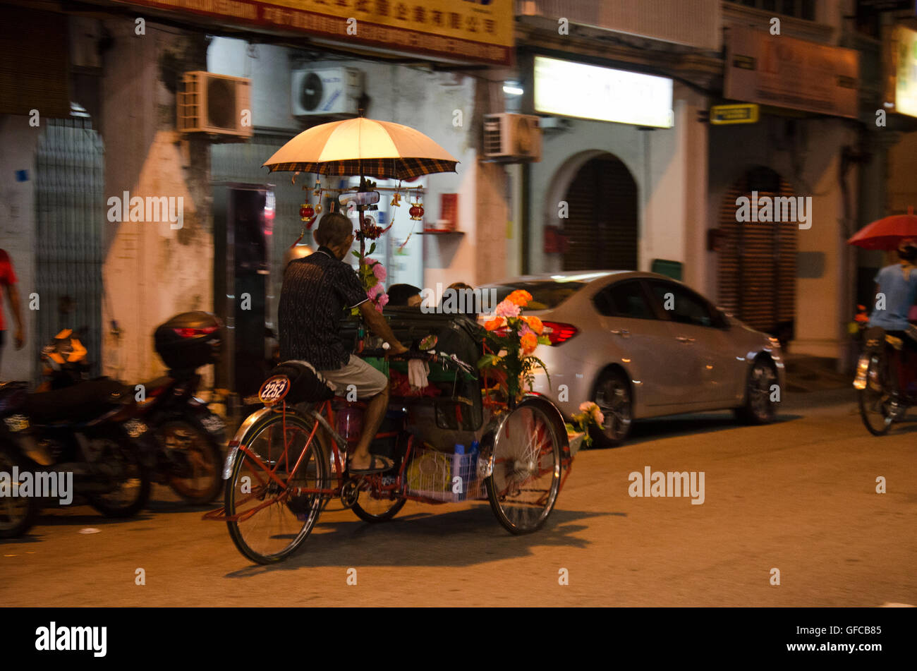 Malaysian persone a cavallo servizio rickshaw viaggiatore tour intorno a Georgetown città e arte di strada area al mercato notturno di alimenti in amore Foto Stock