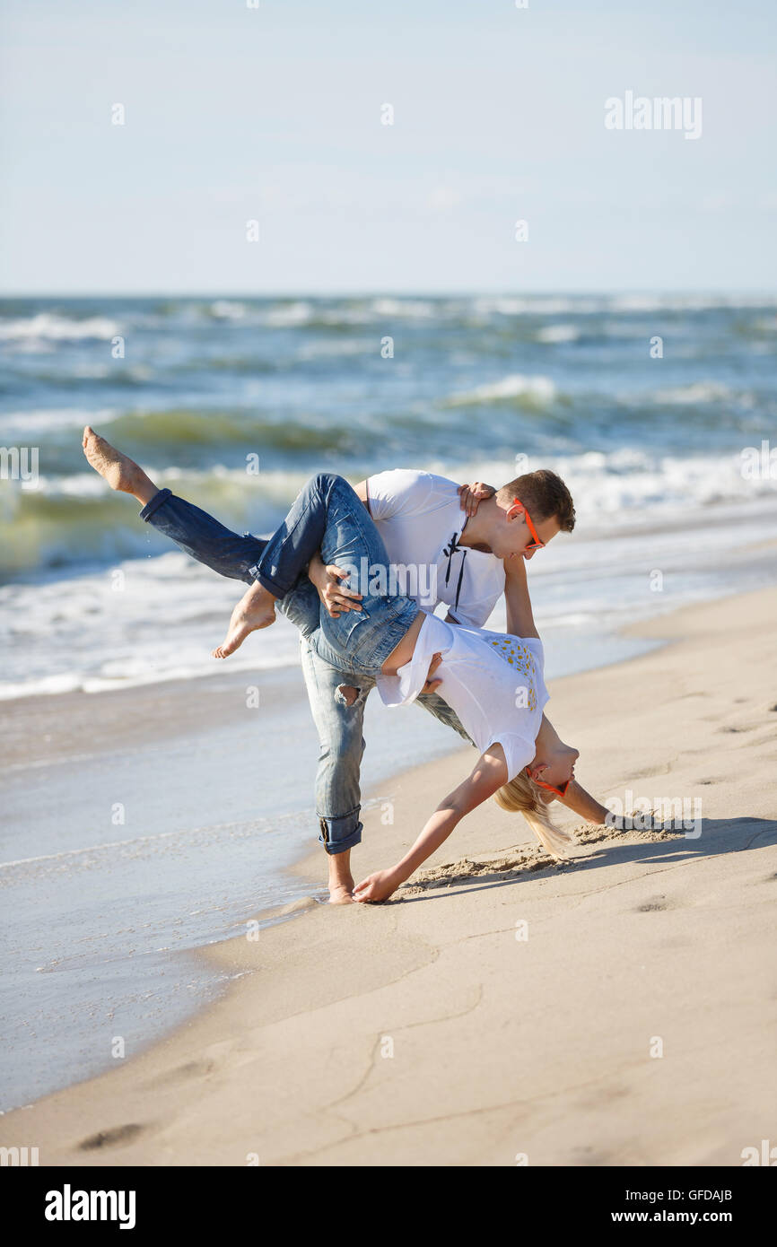 Allegro giovane fanno la danza acrobatica sulla spiaggia, ora legale Foto Stock