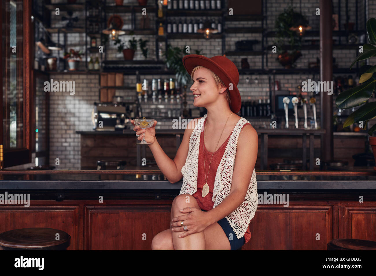 Ritratto di giovane ed elegante donna con un drink presso il cafe. Femmina caucasica seduti al coffee shop counter tenendo un bicchiere di bibita Foto Stock