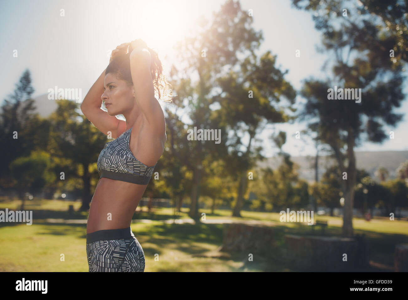 Vista laterale di montare la giovane donna in sportswear ottenere pronto per l'allenamento. Donna sana in park in una giornata di sole. Foto Stock