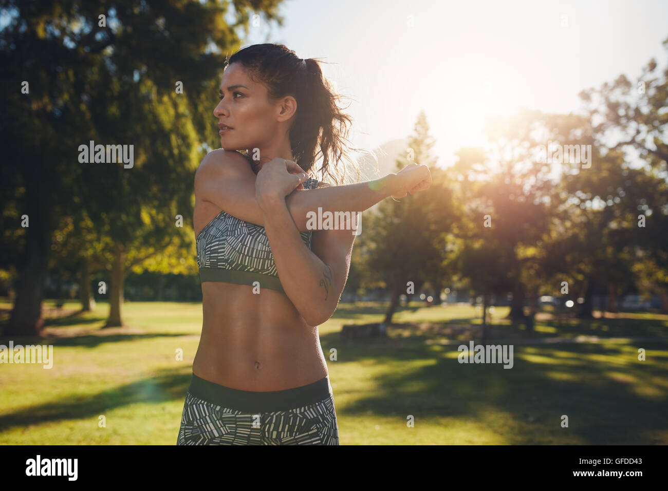 Giovane atleta femminile stretching prima di fitness training session presso il parco. Sano giovane donna in fase di riscaldamento all'esterno. Ella è str Foto Stock