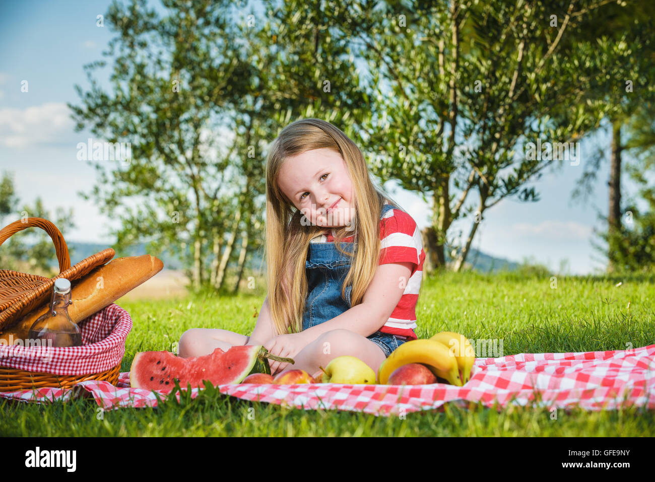 Piccola bella ragazza bionda facendo picnic nel paesaggio della campagna toscana. Foto Stock