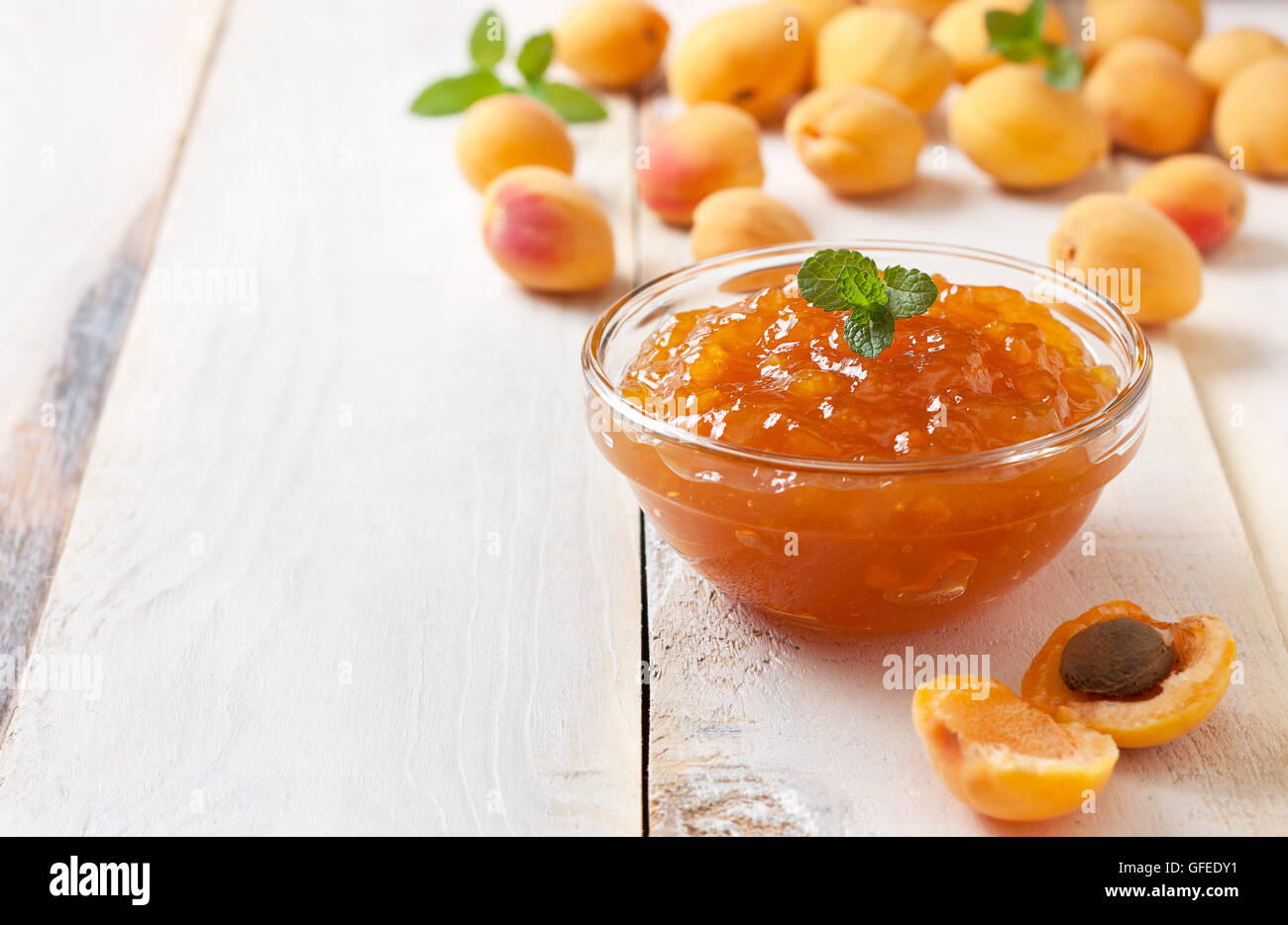 Confettura di albicocche in una ciotola di vetro, fresche Albicocche in un cesto su una luce sullo sfondo di legno Foto Stock