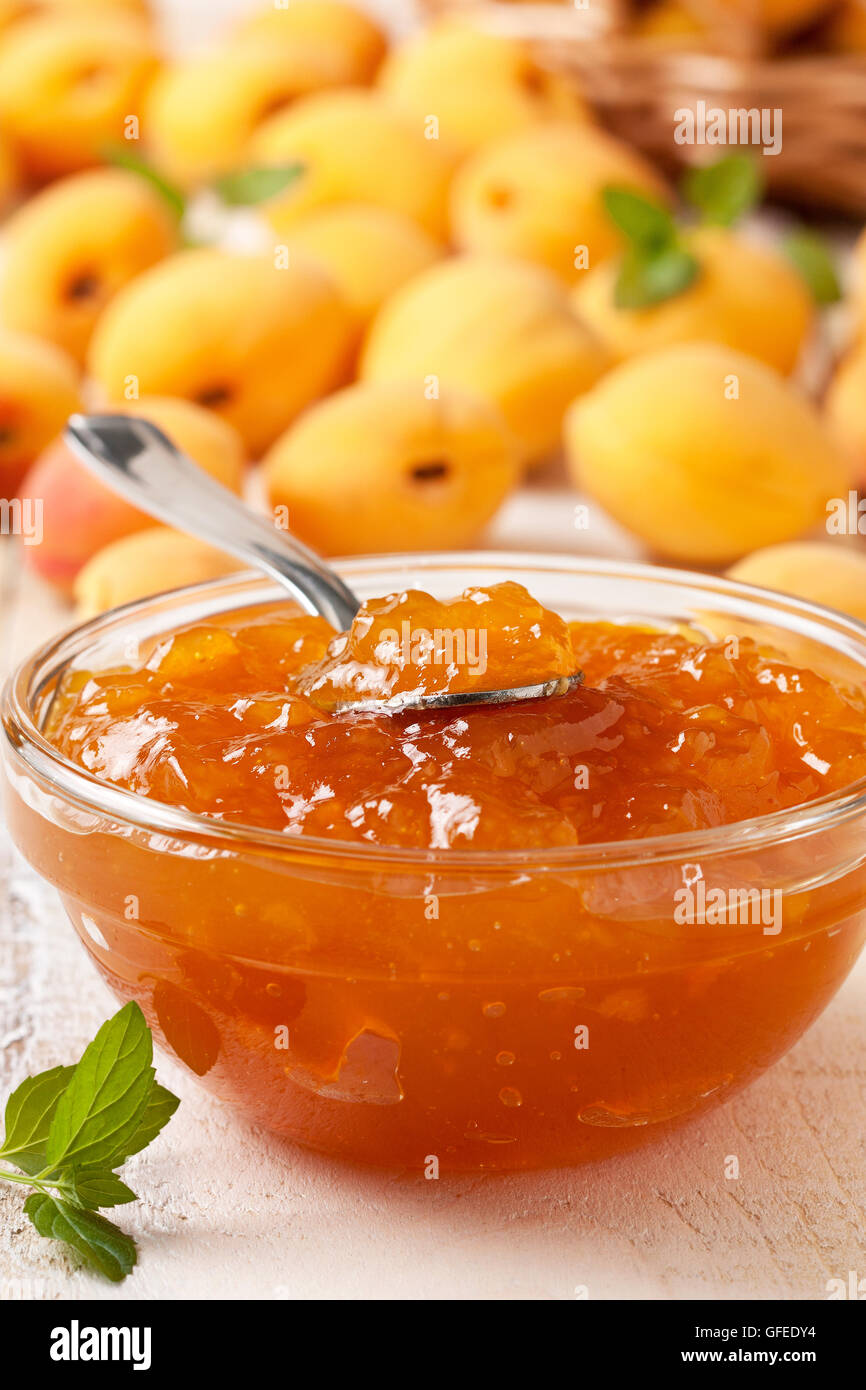 Confettura di albicocche in una ciotola di vetro, fresche Albicocche in un cesto su una luce sullo sfondo di legno Foto Stock