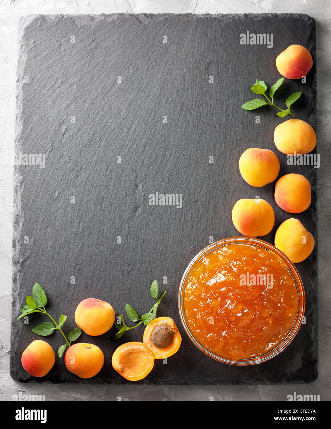 Confettura di albicocche in una ciotola di vetro, fresche Albicocche sulla pietra nera di sfondo (Vista superiore ) Foto Stock
