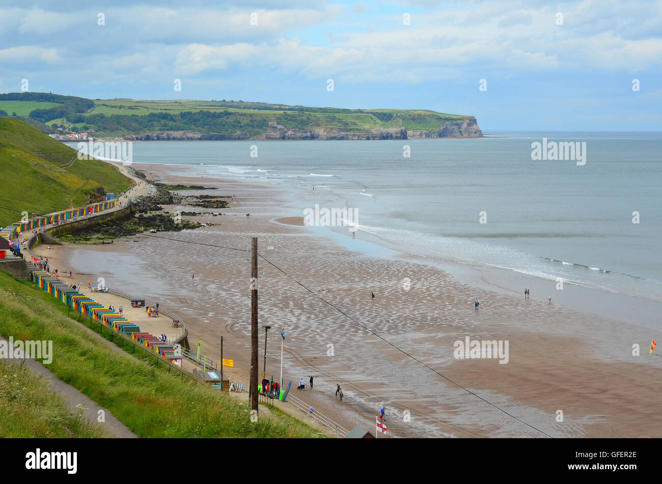 Multi-colore di cabine sulla spiaggia, a Whitby Beach, Whitby, nello Yorkshire, Inghilterra, Regno Unito. Sandsend nella distanza Foto Stock